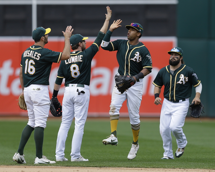 From left, Oakland Athletics&#039; Adam Rosales, Jed Lowrie, Khris Davis and Jaff Decker celebrate a win over the Seattle Mariners at the end of a baseball game Saturday, April 22, 2017, in Oakland, Calif.