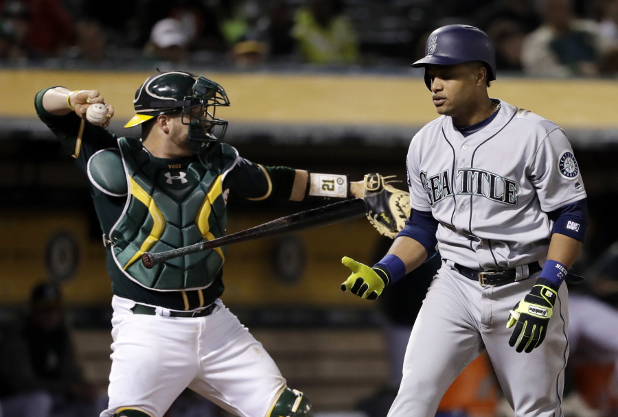 Seattle Mariners&#039; Robinson Cano flips his bat as he strikes out, next to Oakland Athletics catcher Stephen Vogt.