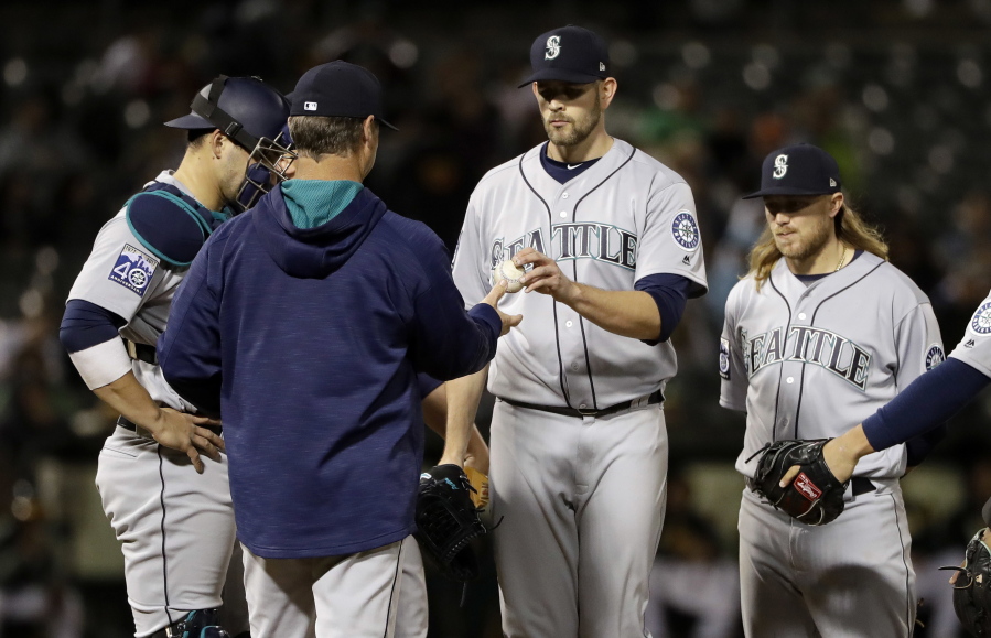 Seattle Mariners starting pitcher James Paxton, center, is pulled from the baseball game by manager Scott Servais during the fifth inning against the Oakland Athletics, Thursday, April 20, 2017, in Oakland, Calif.