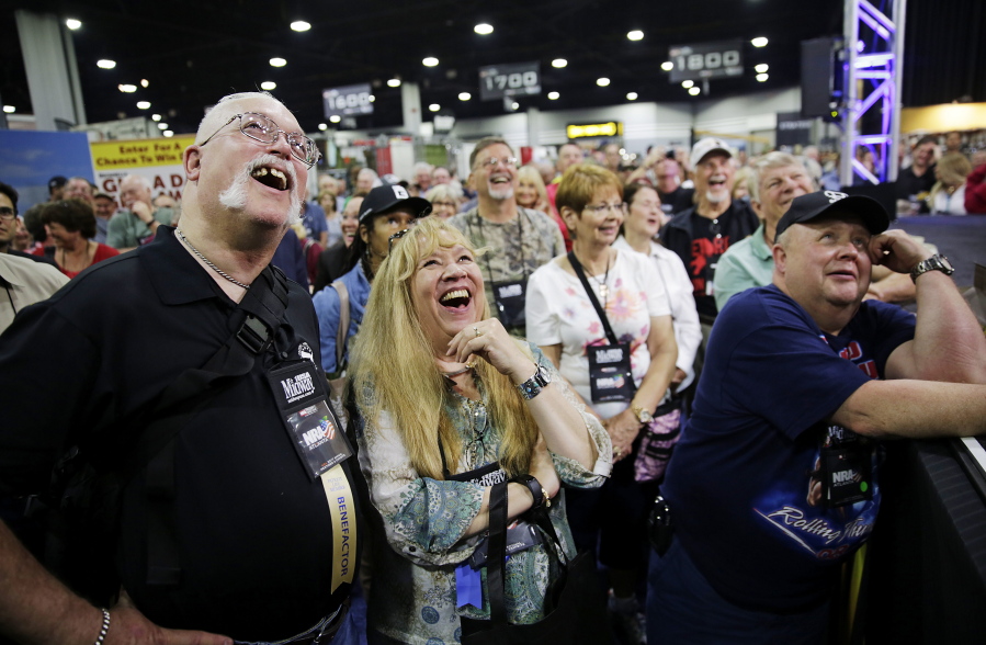 John, left, and Joe Windle of Baltimore watch on a television from the exhibition hall as President Donald Trump speaks Friday at the National Rifle Association&#039;s annual convention in Atlanta.