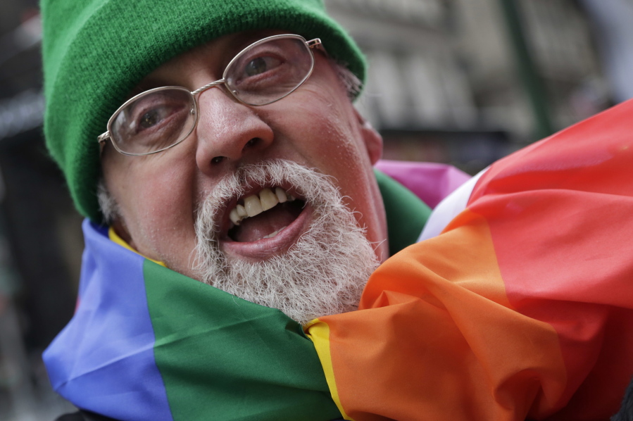 Artist Gilbert Baker, designer of the Rainbow Flag, is draped with the flag while protesting at the St. Patrick&#039;s Day parade in New York on March 17, 2014. Baker, creator of the flag that has become a widely recognized symbol of gay rights, has died at age 65. His death was reported Friday, March 31, 2017 to the New York City medical examinerC?Us office.