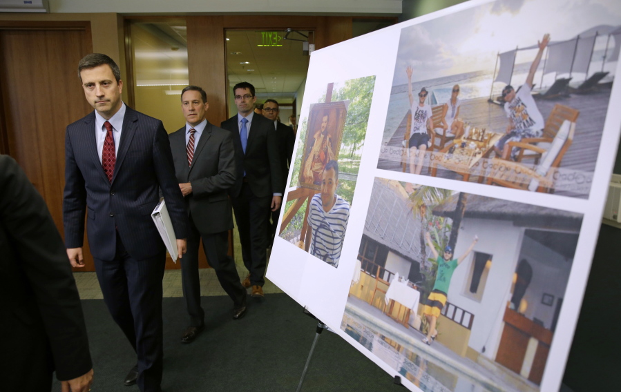 Trevor McFadden, left, acting principal deputy assistant attorney general, and other officials walk past photos of Russian hacker Roman Seleznev as they arrive to talk to reporters Friday in Seattle, following the federal court sentencing of Seleznev to 27 years in prison after he was convicted of hacking into businesses to steal card data. (Photos by Ted S.