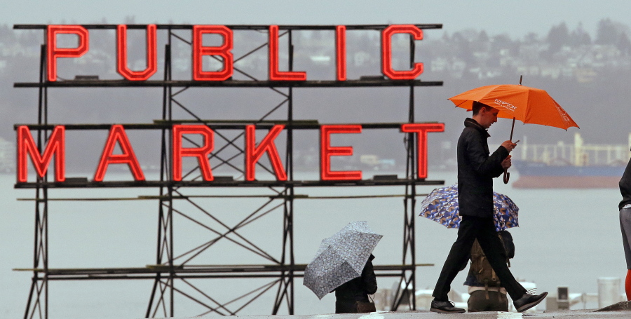 Pedestrians huddle under umbrellas Jan. 18 as they walk past the Pike Place Market and in view of Elliot Bay, behind, in Seattle. The National Weather Service says the city has measured 44.67 inches of rain in the city between October 2016 and so far in April.
