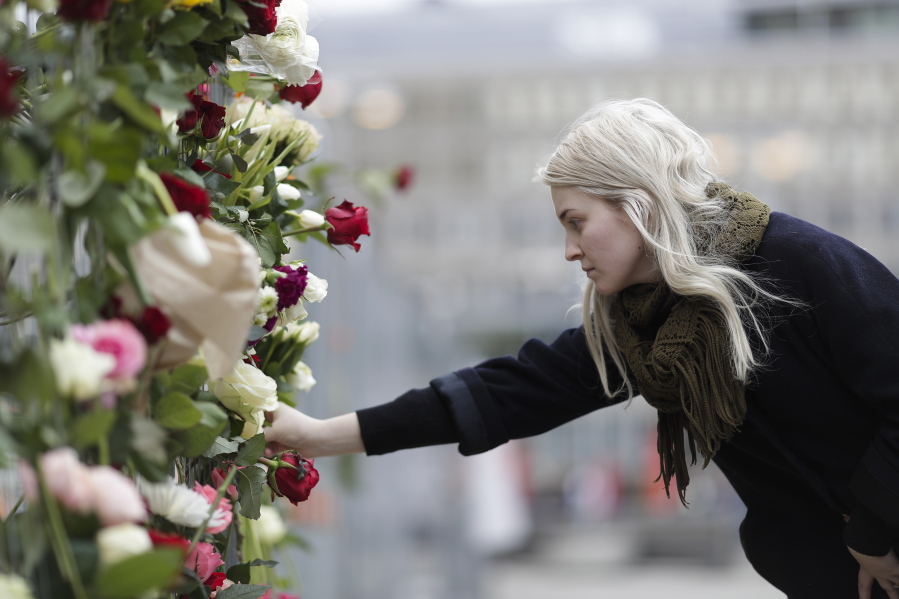 A woman places a flower on a fence Saturday near the site of a suspected terror attack in central Stockholm, Sweden, that killed four people Friday.
