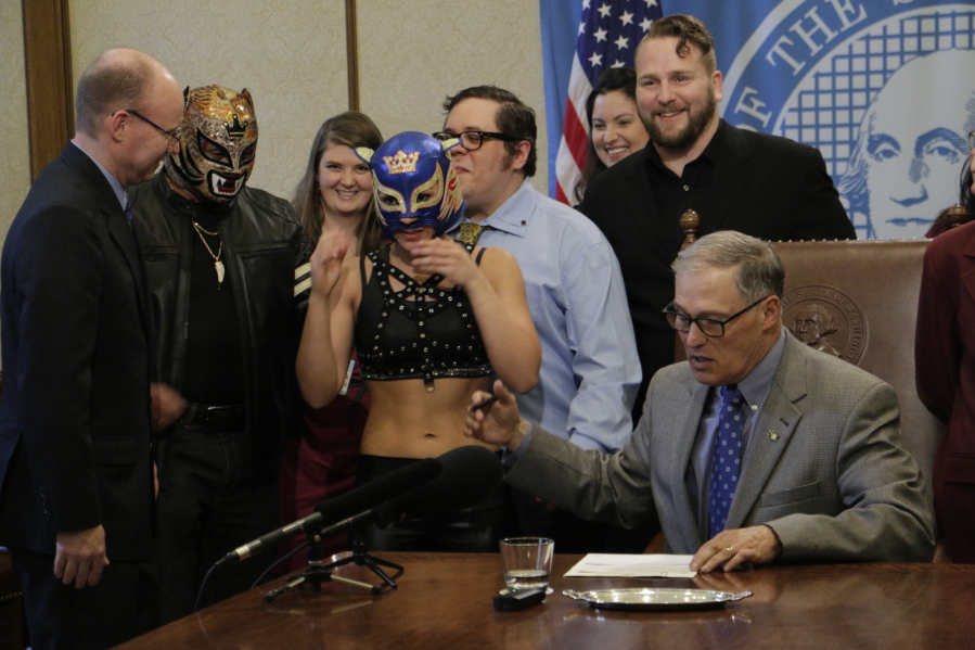 Gov. Jay Inslee talks with supporters of theatrical wrestling Monday in Olympia before signing a bill that creates a license for theatrical wrestling schools. Under the measure, any licensed theatrical wrestling school would be allowed to schedule a certain number of public performances.