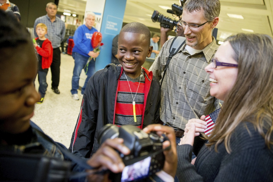 Jennifer and Eric Sands of Illinois, right, and their adopted daughter Joy, 12, left, smile as their adopted son Issaac, 12, center arrives from the Congo in 2015 at Dulles International Airport in Dulles, Va.