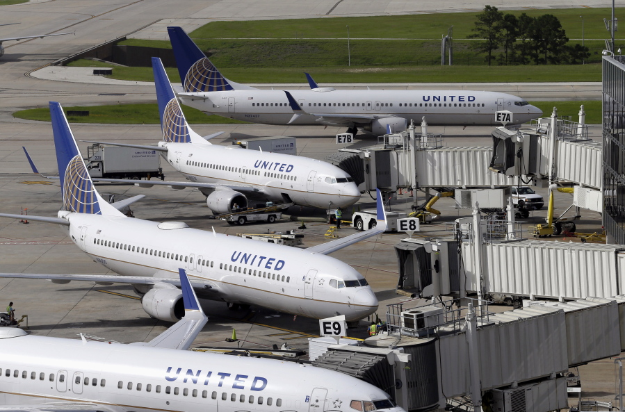 United Airlines planes are parked at their gates as another plane, top, taxis past them at George Bush Intercontinental Airport in Houston on July 8, 2015. United Airlines says it will raise the limit to $10,000 on payments to customers who give up seats on oversold flights and will increase training for employees as it deals with fallout from the video of a passenger being violently dragged from his seat. (AP Photo/David J.