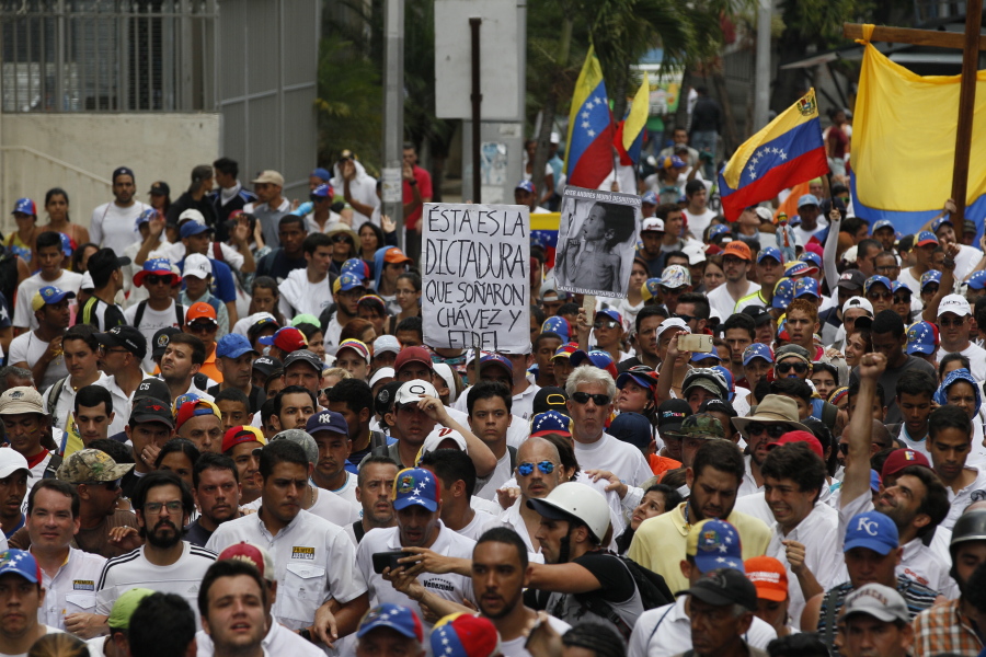 People protest in homage to the at least 20 people killed in unrest generated after the nation&#039;s Supreme Court stripped congress of its last powers, a decision it later reversed, during a silent march to the Venezuelan Episcopal Conference in Caracas, Venezuela, Saturday. The sign reads in Spanish &quot;This is the dictatorship that Chavez and Fidel dreamed of.&quot; In the front of the picture are, from left, lawmaker Tomas Guanipa, lawmaker Miguel Pizarro, lawmaker Jose Manuel Olivares, Miranda state Governor and opposition leader Henrique Capriles, and lawmaker Juan Requesens.
