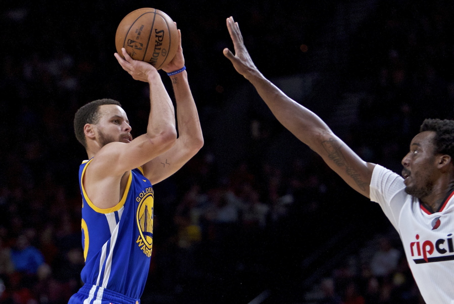 Golden State&#039;s Stephen Curry, left, shoots a three-point basket over Portland&#039;s Al-Farouq Aminu during the first half Monday.