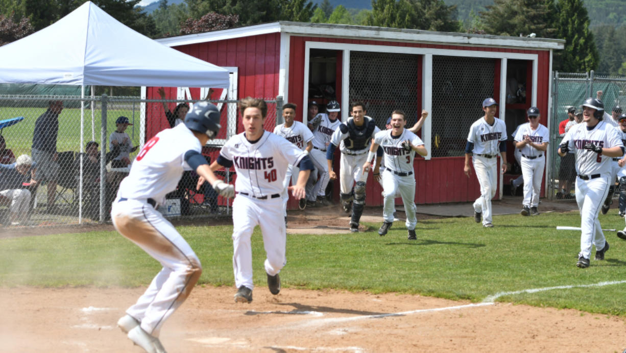 The King's Way Christian baseball team spills out of the dugout after Damon Casetta-Stubbs slides home with the winning run against Cascade Christian.