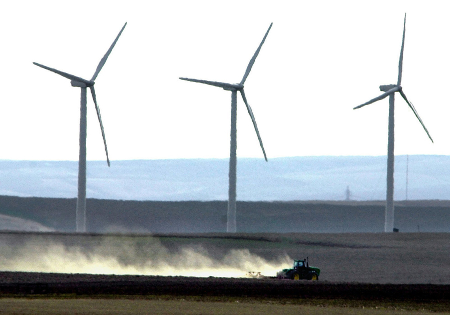 Wind turbines tower over a tractor and plow tilling farmland near Wasco, Ore., March 4, 2002. Eastern Oregon finds itself struggling to balance the move into green energy with the needs and concerns of the region’s farmers.