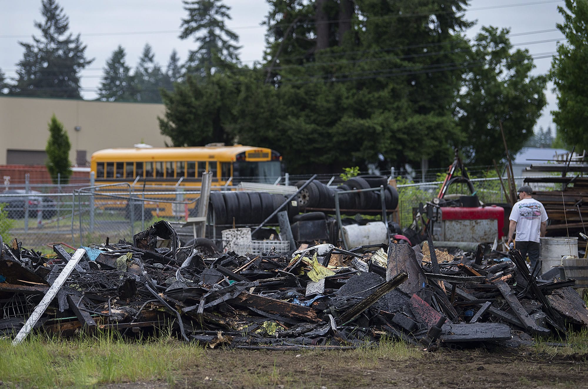 A school bus, top, passes Covington Middle School as the charred remains of a structure in Orchards are seen nearby Thursday morning.