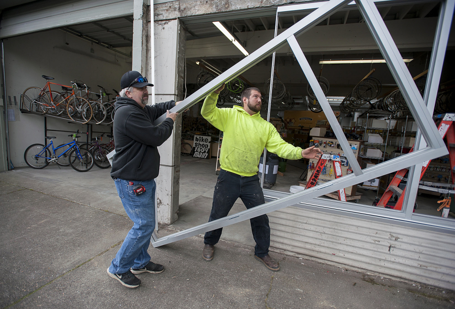 Jason Sheffield, left, and Alex Braman of River City Glass prepare to install front windows for Bike Clark County.