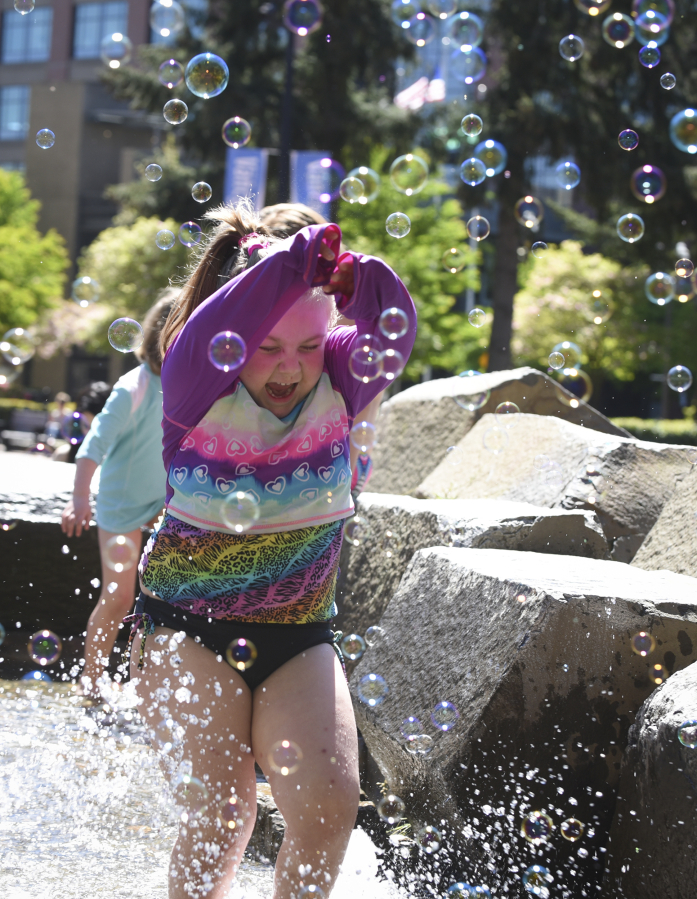 Ruby Smith, 5, runs through bubbles in the water fountain Wednesday at Esther Short Park in downtown Vancouver. While temperatures reached the low 80s Wednesday and some of that warmth may linger today, expect to see clouds and more rain to roll in tonight.