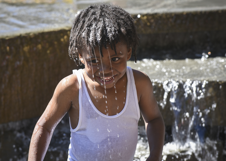 Damarius Jerman, 4, looks up at his grandmother Wednesday after dumping water on his head in the water fountain at Esther Short Park in downtown Vancouver.(Ariane Kunze/The Columbian)