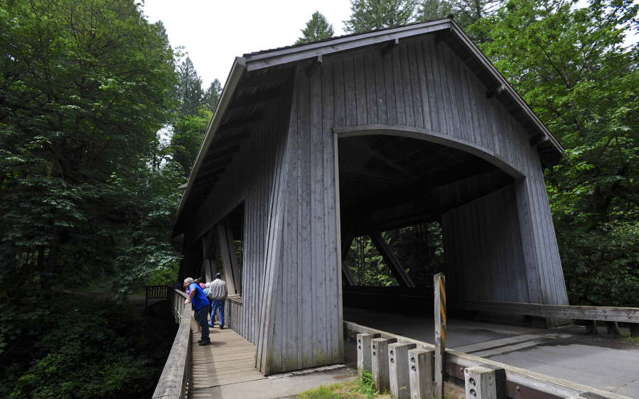 Visitors check out the covered bridge on Grist Mill Road next to at the Cedar Grist Mill.
