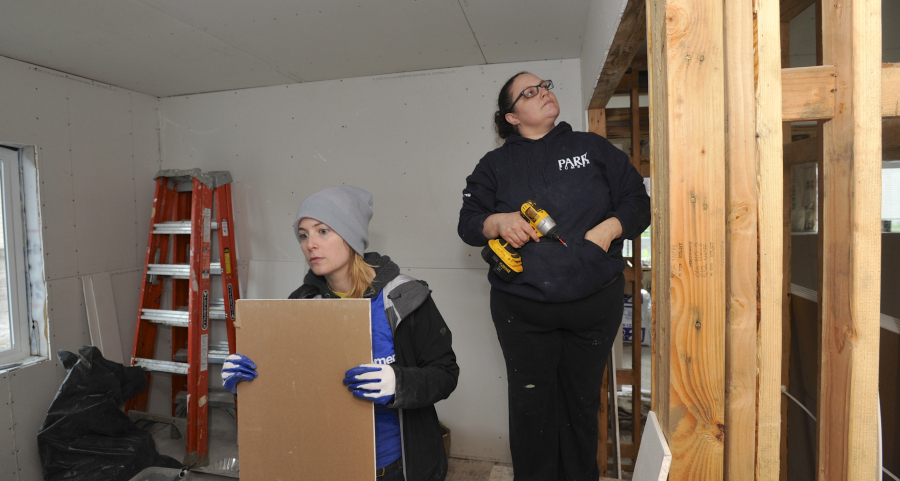 Greg Wahl-Stephens for the Columbian
A volunteer for Evergreen Habitat for Humanity, Lydia Waik, left, hangs sheetrock with homeowner Crystal Helsel on Saturday during Habitat’s 10th annual National Women Build Week. Helsel’s home is one of 10 in the McKibbin Commons subdivision in Vancouver’s Father Blanchet Park neighborhood.