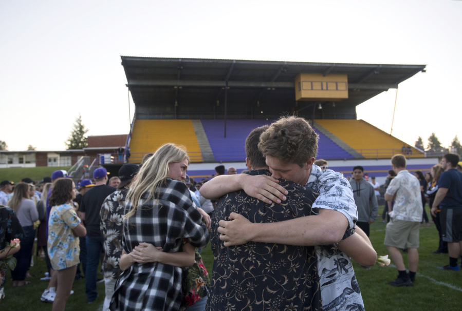 Columbia River High School senior Ethan Adams, 18, in tan and black shirt, and junior Ryan Connop, 17, right, lean on each other for support as they pause to honor the memory of their friend, Hunter Pearson, on the school’s football field Monday evening, May 29, 2017. Hunter Pearson, a senior and football player, presumably drowned Saturday in a swimming accident at Lacamas Lake. Students wore Hawaiian shirts to honor his sense of style.