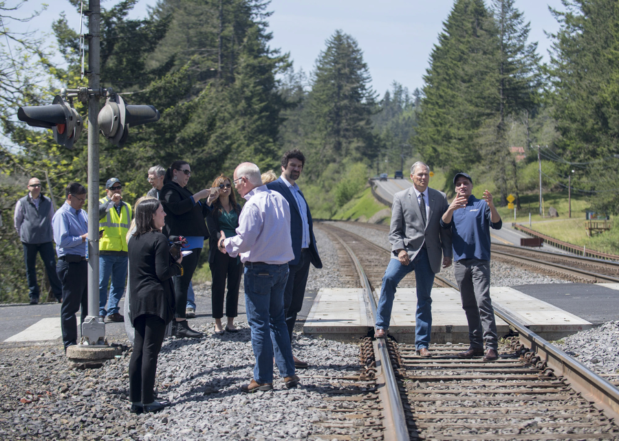 Gov. Jay Inslee, second from right, is escorted by BNSF Railway spokesman Gus Melonas as they gather with others Tuesday afternoon at a Skamania County rail crossing to learn more about rail safety.