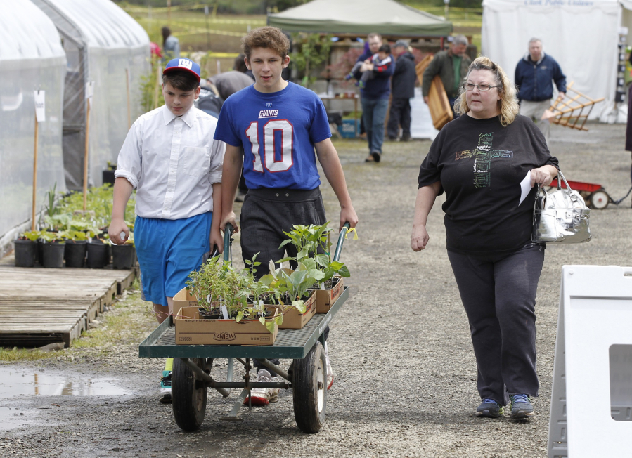 Steve Dipaola for The Columbian
Eleven-year-old Randall Conner, from left, 13-year-old Greg Conner and their mother, Terry Conner, leave the Master Gardener Foundation of Clark County’s annual plant sale Sunday. Many plant sale guests brought, or were shopping for, mom.