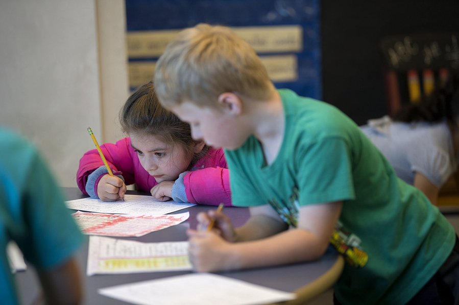 Amanda Cowan/The Columbian
First-grader Mariana Neal, left, keeps her focus on her schoolwork as classmate Max Miller attends to his own work at Washington Elementary School on Wednesday morning. Vancouver Public Schools will eliminate homework for K-3 students next year, instead encouraging families to do activities together.