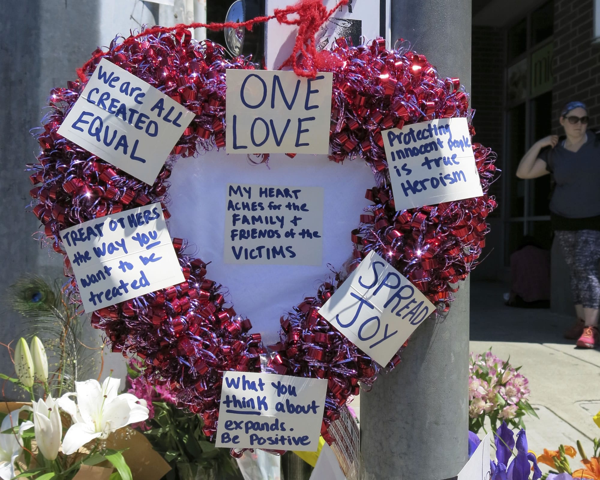A heart-shaped wreath covered with positive messages hangs on a traffic light pole at a memorial for two bystanders who were stabbed to death Friday, while trying to stop a man who was yelling anti-Muslim slurs and acting aggressively toward two young women, including one wearing a Muslim head covering, on a light-trail train in Portland, Ore, Saturday, May 27, 2017. A memorial grew all day Saturday outside the transit center in Portland, as people stopped with flowers, candles, signs and painted rocks. Jeremy Joseph Christian, 35, was booked on suspicion of murder and attempted murder in the attack.
