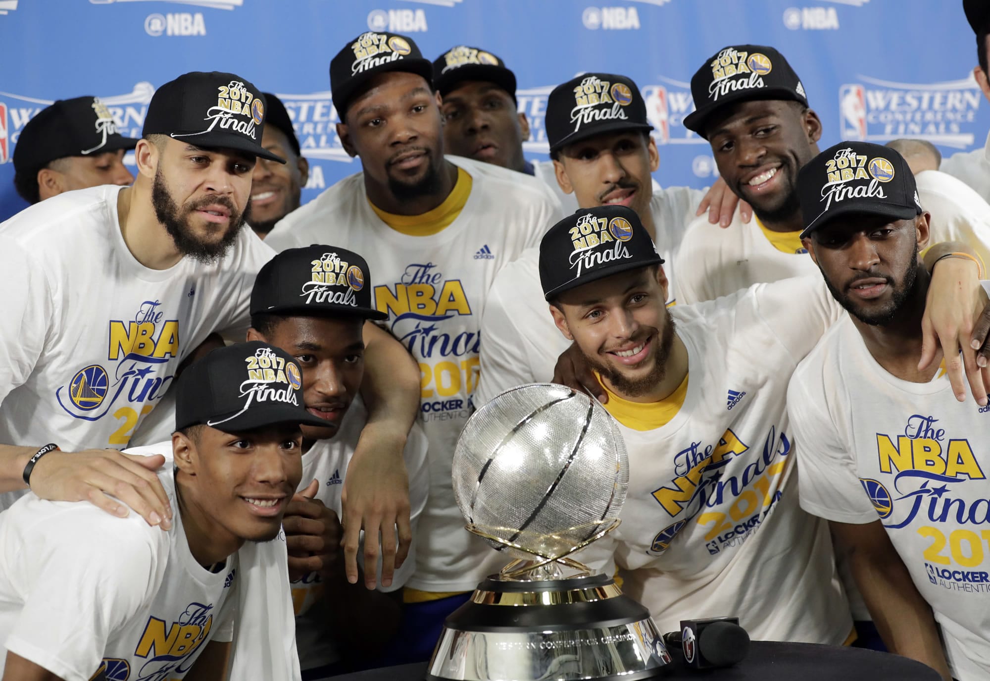 Golden State Warriors' JaVale McGee, top left, Kevin Durant, top center, Stephen Curry, center right, and Draymond Green, top right, join the rest of their team as they pose with the trophy after their 129-115 win over the San Antonio Spurs in Game 4 of the NBA basketball Western Conference finals, Monday, May 22, 2017, in San Antonio.