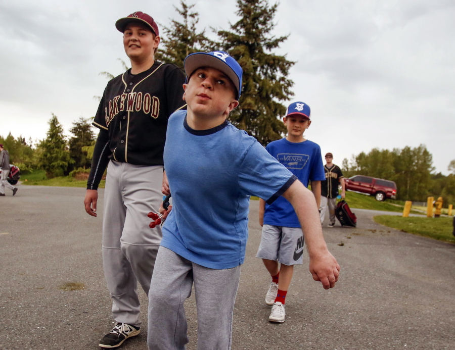 Older brother Jacob Irish, 16, from left, leads siblings Matthew, 15, and Noah, 11, as they walk to their car from the baseball field May 4 at Lakewood Middle School after games were canceled by lightning in Marysville.