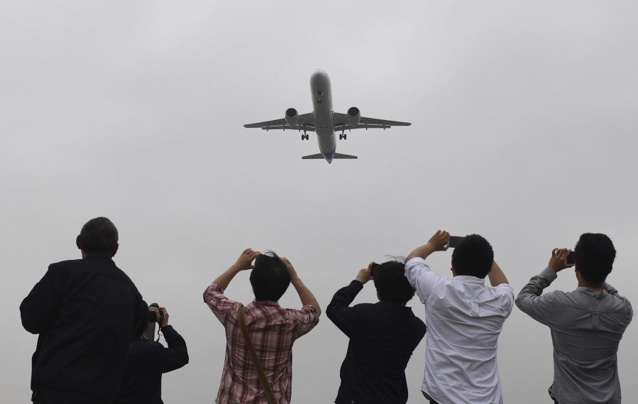 Spectators take photos as they watch the Comac C919, China&#039;s first large passenger jet, coming in for a landing on its maiden flight at Shanghai&#039;s Pudong airport, China, Friday May 5, 2017.