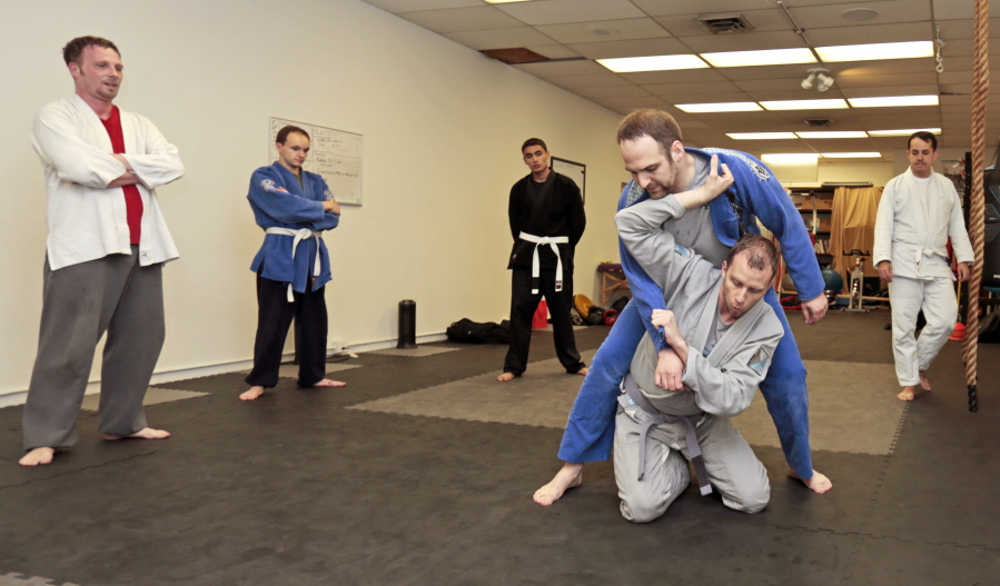 Jiujitsu instructor Shane McFarland, in grey, uses student Turner McCulley, in blue, to demonstrate a throw during a class May 17 at his studio in Pullman.