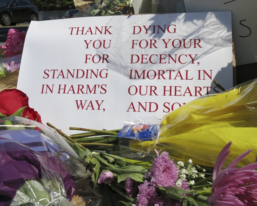 A sign of thanks rests against a traffic light pole at a memorial outside the transit center in Portland, Ore. on Saturday. People stopped with flowers, candles, signs and painted rocks for two bystanders who were stabbed to death Friday, while trying to stop a man who was yelling anti-Muslim slurs and acting aggressively toward two young women, including one wearing a Muslim head covering, on a light-trail train in Portland. Suspect Jeremy Joseph Christian, 35, was booked on suspicion of murder and attempted murder in the attack and will make a first court appearance Tuesday.