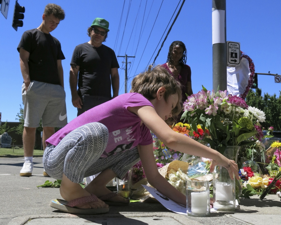 Coco Douglas, 8, leaves a handmade sign and rocks she painted at a memorial Saturday in Portland, for two bystanders who were stabbed to death Friday while trying to stop a man who was yelling anti-Muslim slurs and acting aggressively toward two young women. From left are Coco’s brother, Desmond Douglas; her father, Christopher Douglas; and her stepmother, Angel Sauls.