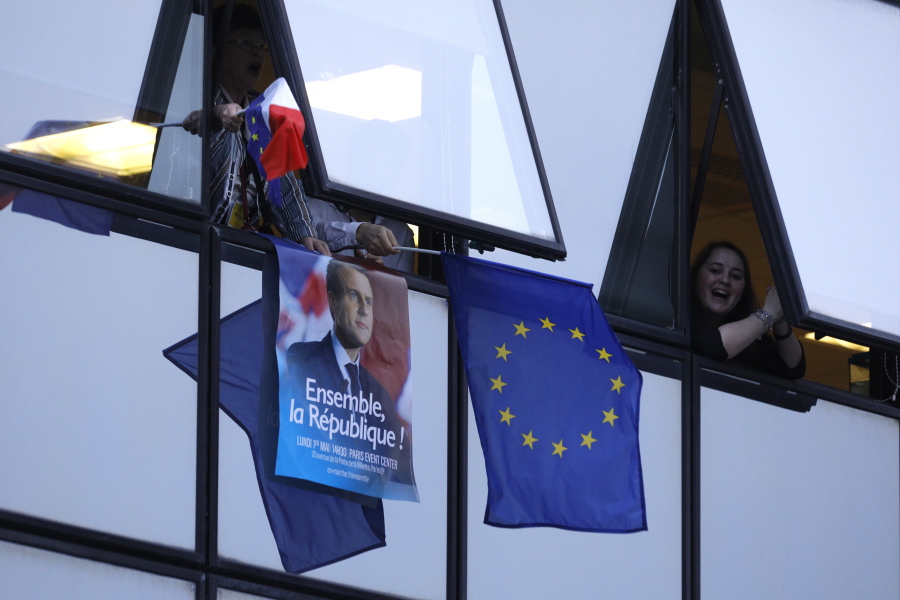 Parisians wave an European flag and a portrait of Macron after French polling agencies project 65 percent of votes for a presidential candidate went to centrist candidate Emmanuel Macron, on Sunday in Paris.