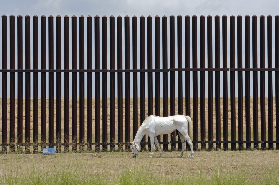A horse grazes the land Friday, May 12, 2017, along the U.S. Border Wall in Brownsville, Texas. Before the wall, there was the fence. And the U.S. is still paying for it. As President Donald Trump tries to persuade a skeptical Congress to fund his proposed multibillion-dollar wall on the Mexican border, government lawyers are still settling claims with Texas landowners over a border fence approved more than a decade ago. Two settlements were completed just this week.