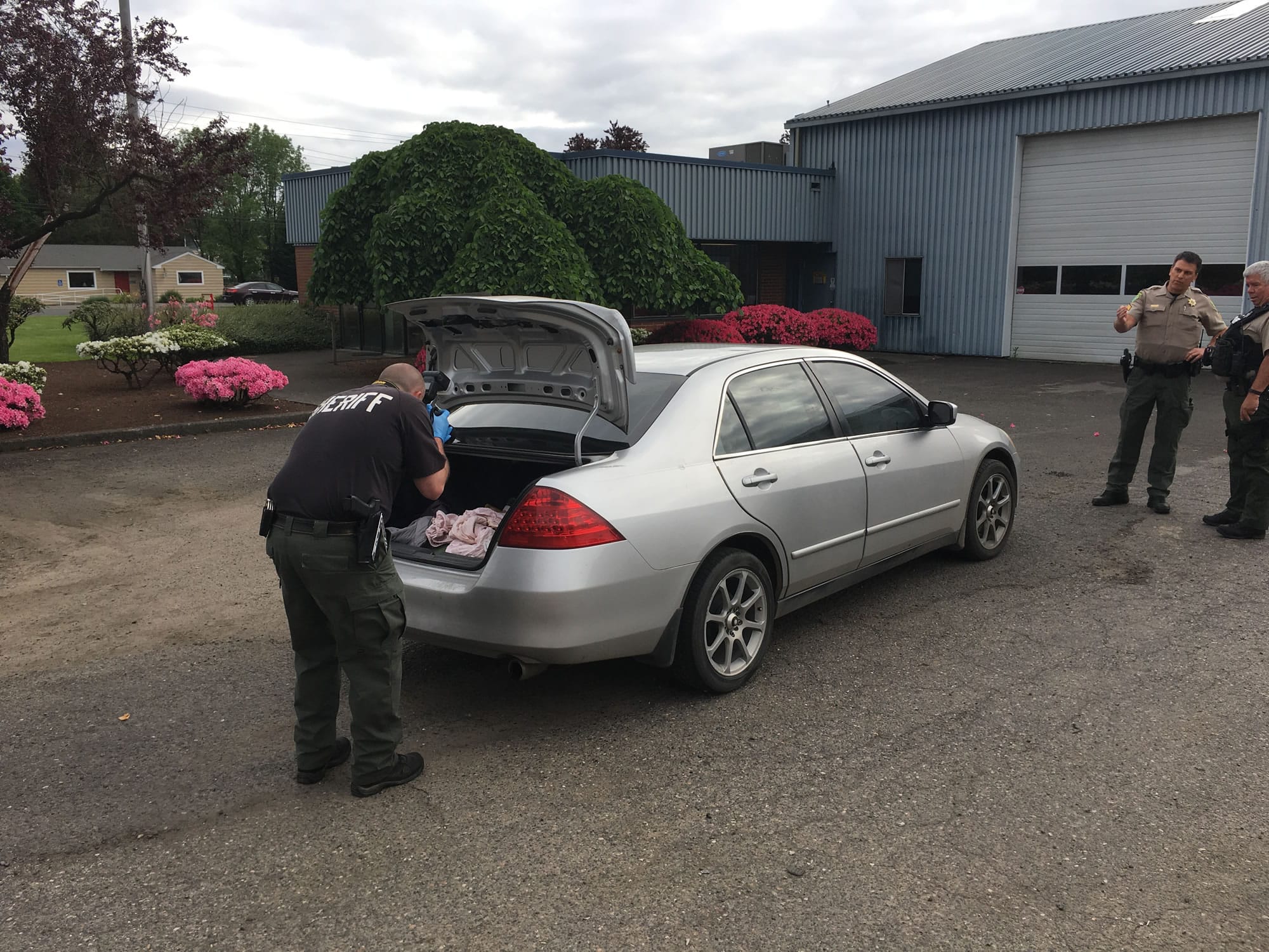 A detective photographs contents of a car's trunk as part of a domestic violence investigation Wednesday morning in Hazel Dell.