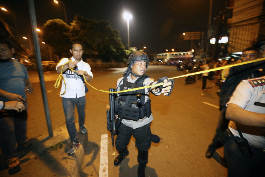 Police officers hold clear the scene after an explosion near a bus stop in the Kampung Melayu area of Jakarta, Indonesia, on Wednesday. Police say a suspected suicide bomb blast near a bus terminal in Indonesia’s capital has killed a policeman and injured four other officers.