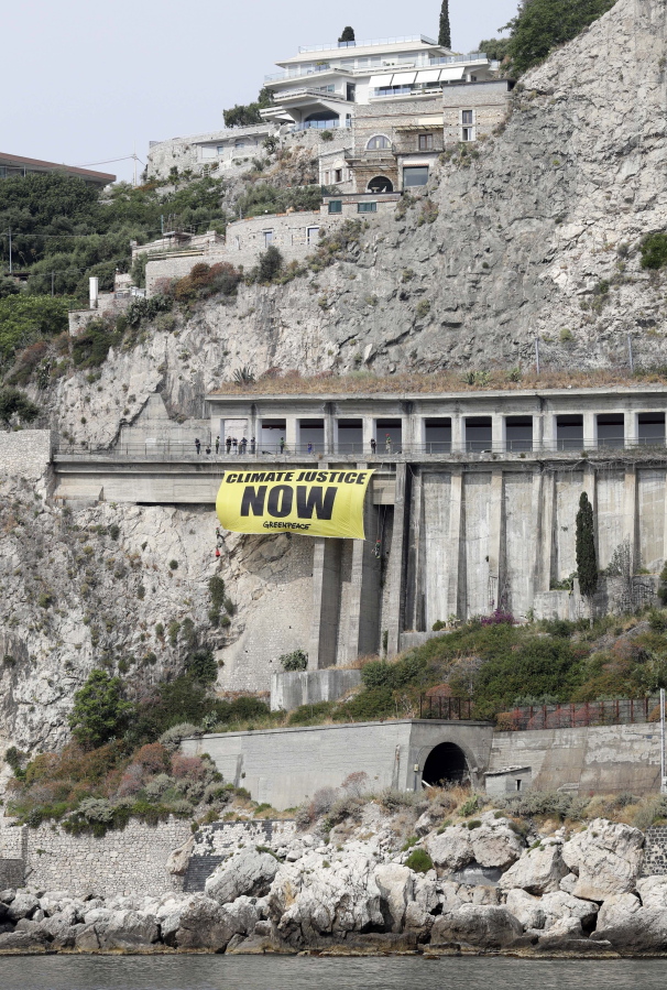 Greenpeace activists hang a banner on climate issues Thursday along a road above the beach of Isolabella, ahead of a G7 summit scheduled for today and Saturday, in the Sicilian town of Taormina, southern Italy.