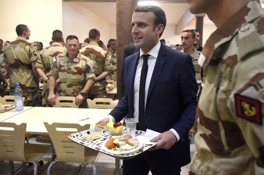 French President Emmanuel Macron arrives with a plate of food Friday as he shares a lunch break with soldiers of Operation Barkhane, France’s largest overseas military operation, in Gao, northern Mali. On his first official trip outside Europe, new French President Emmanuel Macron is highlighting his determination to crush extremism with a visit to French-led military forces combating jihadist groups in West Africa.