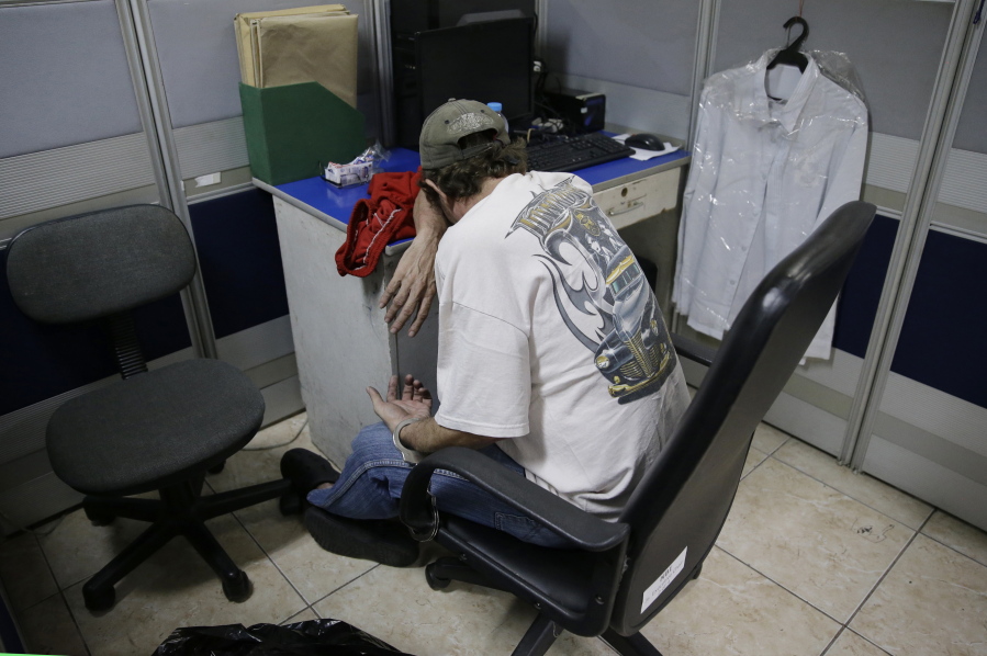In this April 21, 2017 photo, suspected child webcam cybersex operator, American David Timothy Deakin, rests as he is handcuffed to a chair after his arrest at the National Bureau of Investigation in Manila, Philippines. Authorities in the Philippines have arrested three women who were livestreaming sexually exploitative videos of girls to men paying by the minute to watch from half a world away. The incident came just two weeks after Deakin’s arrest where authorities gathered one of the largest seizures of illicit digital content in the country.