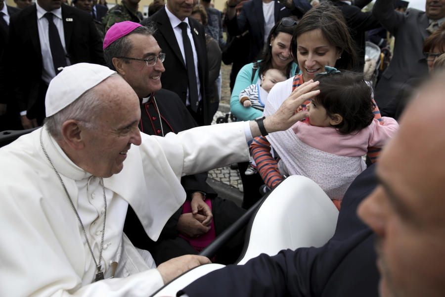 Pope Francis greets a child as he arrives at the Monte Real Air Base in Leiria, Portugal, Friday, May 12, 2017. Pope Francis will canonize on Saturday in Fatima two poor, illiterate shepherd children whose visions of the Virgin Mary 100 years ago marked one of the most important events of the 20th-century Catholic Church.