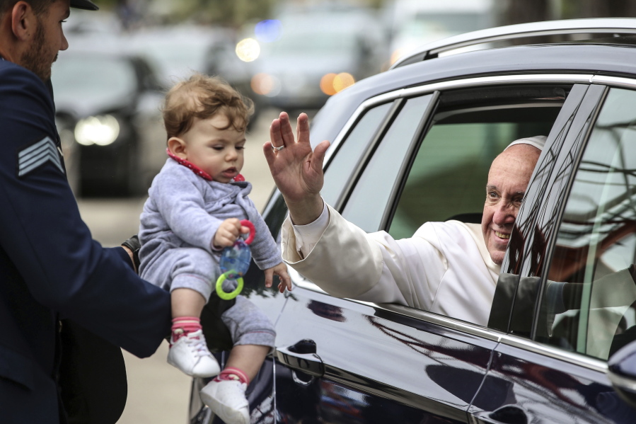 Pope Francis blesses a child upon his departure from Monte Real Air Base, in Leiria, Portugal, Saturday. Pope Francis urged Catholics on Friday to “tear down all walls” and spread peace as he traveled to this Portuguese shrine town to canonize two poor, illiterate shepherd children whose visions of the Virgin Mary 100 years ago marked one of the most important events of the 20th-century Catholic Church.