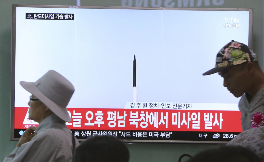 People walk by a TV news program showing a file image of a missile launch conducted by North Korea, at the Seoul Railway Station in Seoul, South Korea, on Sunday. North Korea on Sunday fired a midrange ballistic missile, U.S. and South Korean officials said, in the latest weapons test for a country speeding up its development of nuclear weapons and missiles.