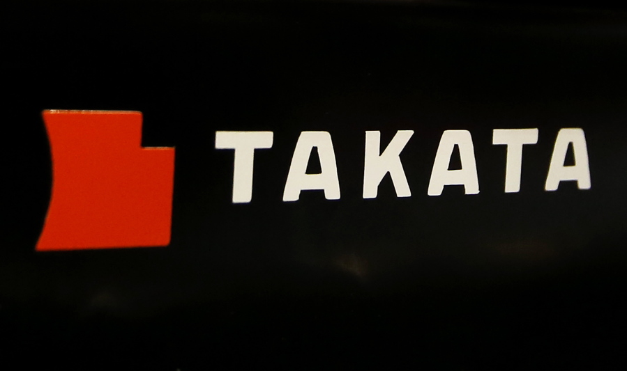 The logo of Takata Corp. is seen at an auto supply shop in Tokyo. On Thursday, Toyota, Subaru, Mazda and BMW reached a proposed settlement that would compensate owners of 15.8 million vehicles for economic losses stemming from the massive recall of Takata air bags.