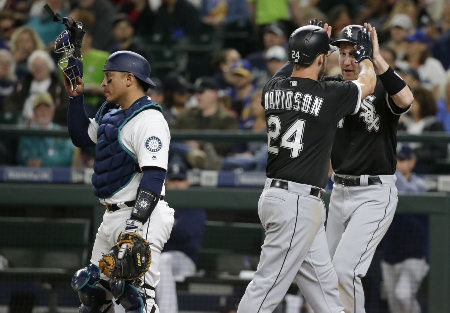 Chicago White Sox's Matt Davidson (24) is greeted by Todd Frazier, right, as Seattle Mariners catcher Carlos Ruiz, left, looks on after Frazier scored on a home run hit by Davidson in the seventh inning of a baseball game, Saturday, May 20, 2017, in Seattle. (AP Photo/Ted S.
