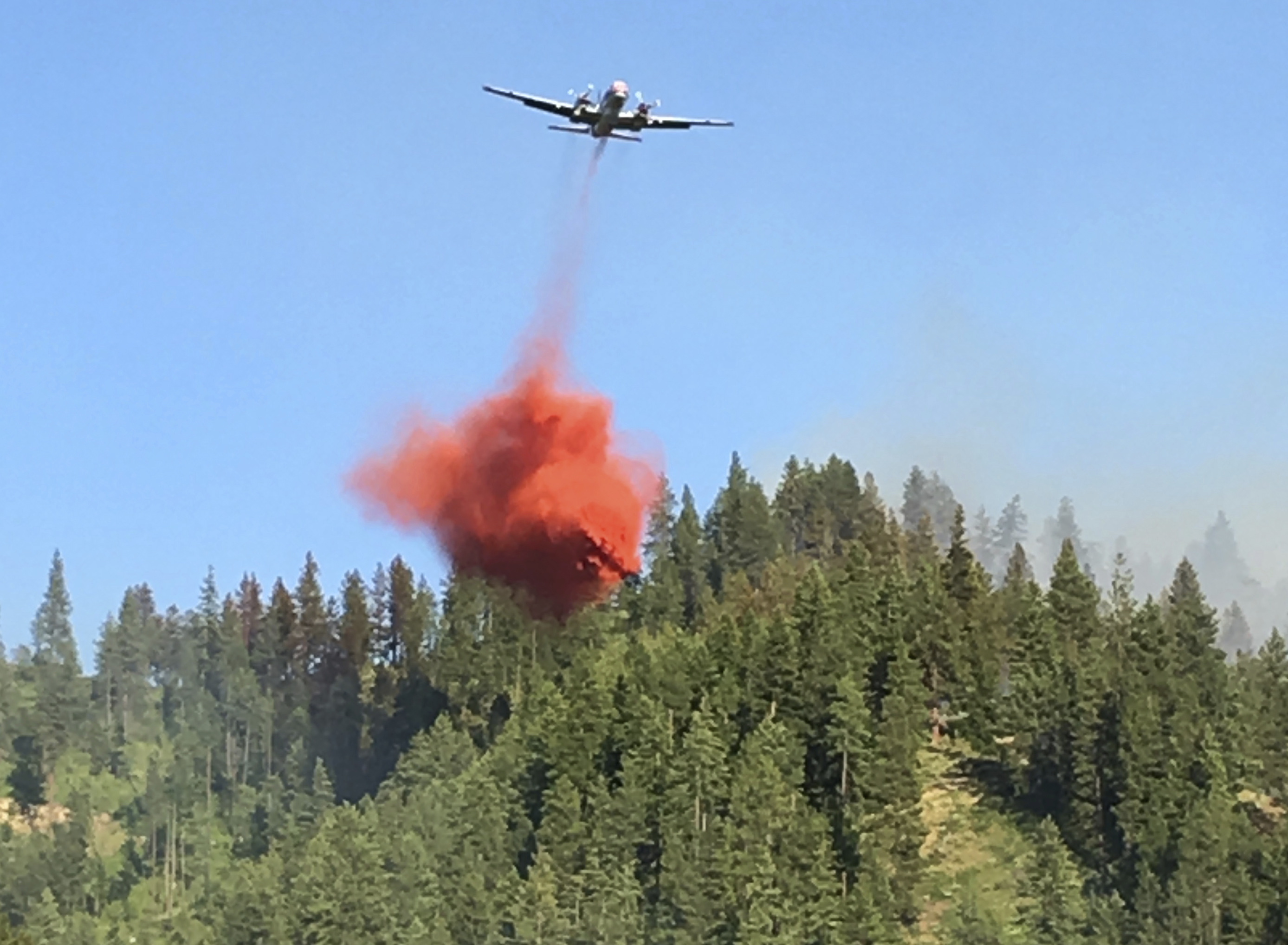 In this May 23, 2017 photo provided by Chelan County Fire District 3, an air tanker drops fire retardant on forest land as a wildfire burns near Leavenworth, Wash. The wildfire that started at an old log-storage site has prompted evacuation orders for homes and cabins at a popular Washington state hiking and skiing destination, officials said Wednesday.