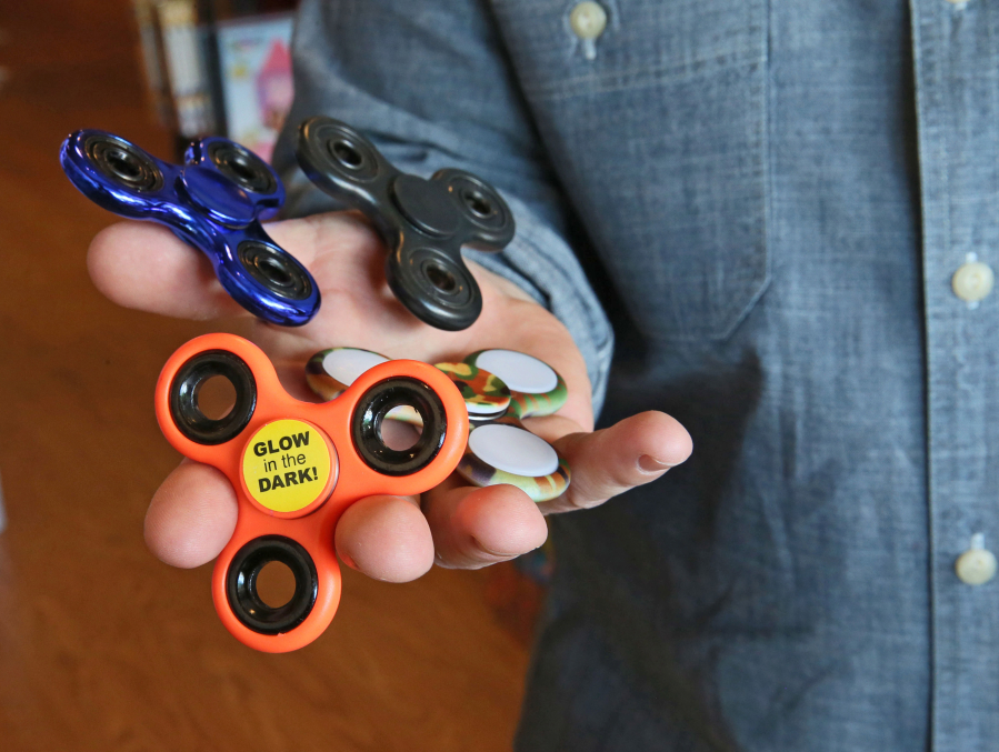 Matthew Poulson, co-owner of Ruckus & Glee in Wauwatosa shows the popular fidget spinners, which look like toys but are being used by adults as well.