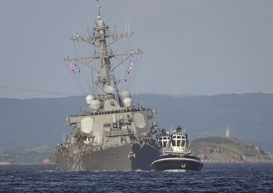 A tugboat tows the damaged USS Fitzgerald on Saturday near the U.S. naval base in Yokosuka, Japan. The destroyer collided with a container ship in the pre-dawn hours.