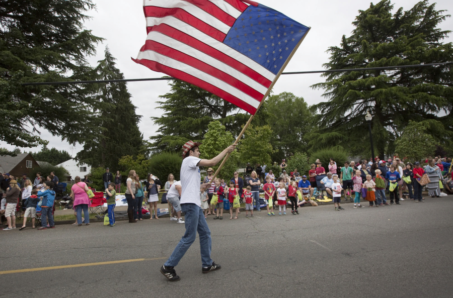 Josh Surdu waves a giant flag as he takes part in the Fourth of July Parade through Ridgefield.