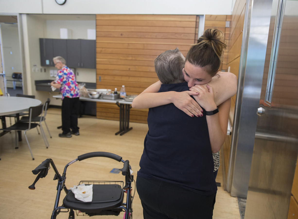 Ginger Meggison of Salmon Creek, center, hugs Lacey Acklin, facing, of Meals on Wheels at the nonprofit’s final lunch Friday at the Firstenburg Community Center. “I’m really going to miss it,” Meggison said.