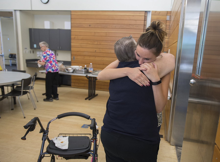 Ginger Meggison of Salmon Creek, center, hugs Lacey Acklin, facing, of Meals on Wheels at the nonprofit’s final lunch Friday at the Firstenburg Community Center. “I’m really going to miss it,” Meggison said.